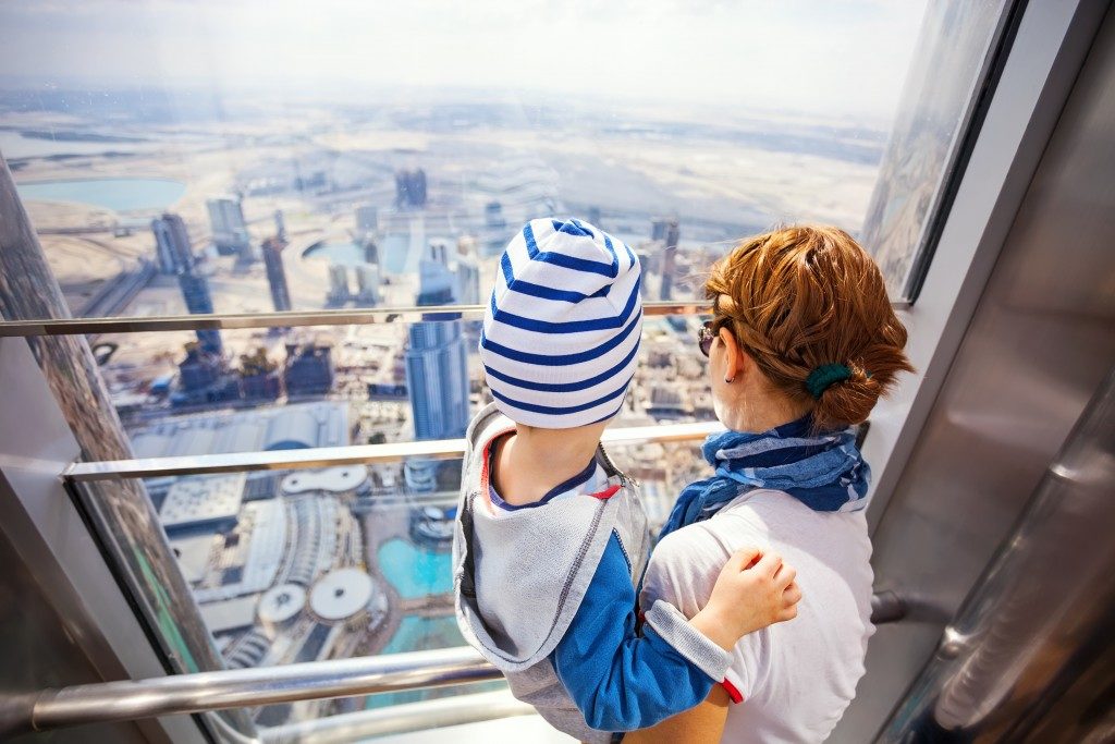 woman and child in an elevator overlooking dubai