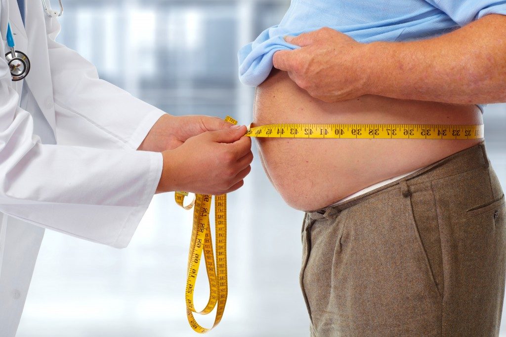 doctor checking man's waistline