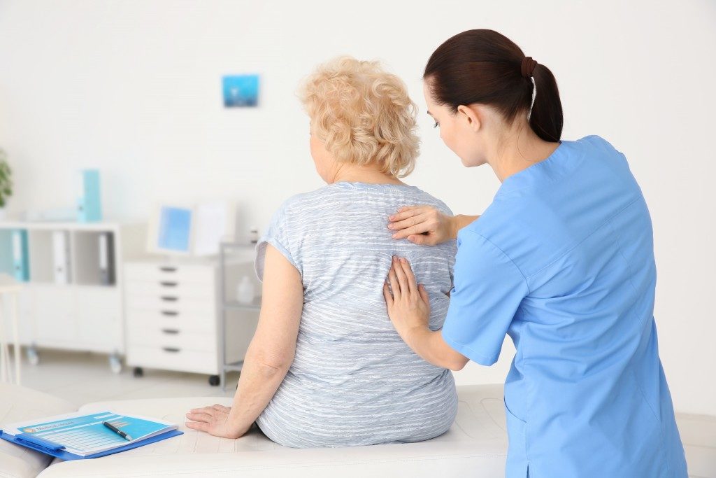 physiotherapist checking on elderly woman's spine