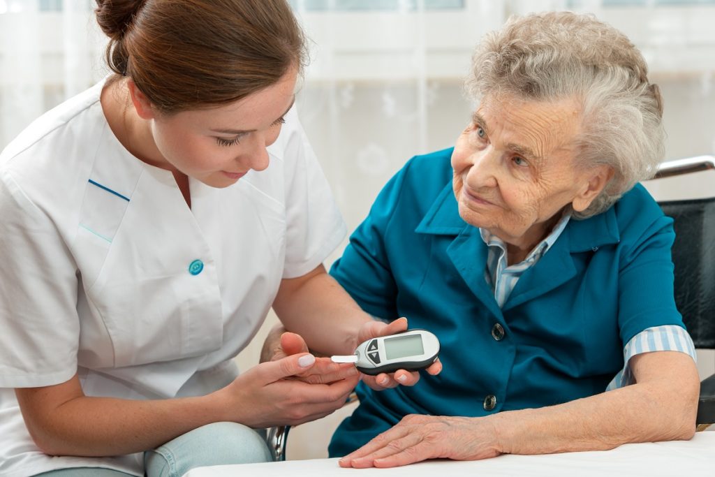 nurse checking blood sugar level of old woman