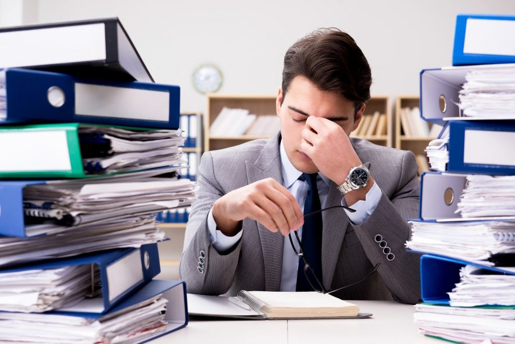 Man with piles of paperwork on his office desk