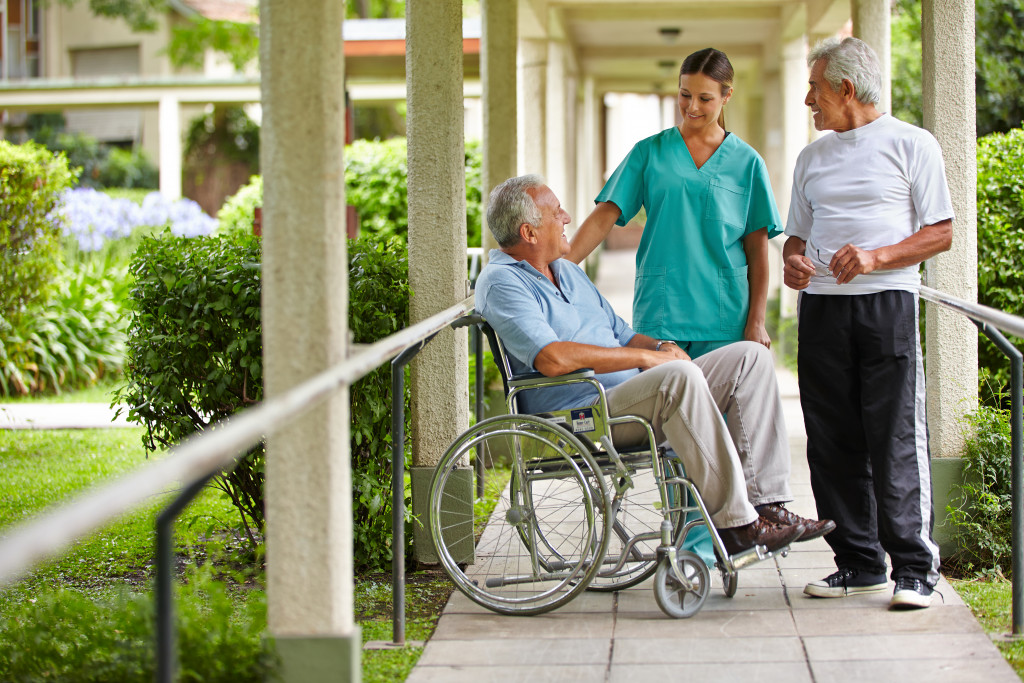 Two senior citizens talking to a nurse in a garden