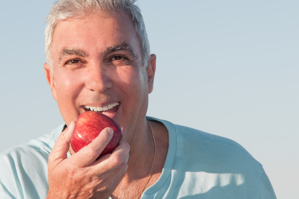 middle aged man eating an apple