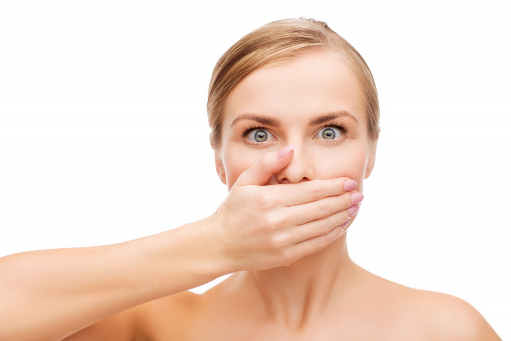 woman with bad breath covering her mouth